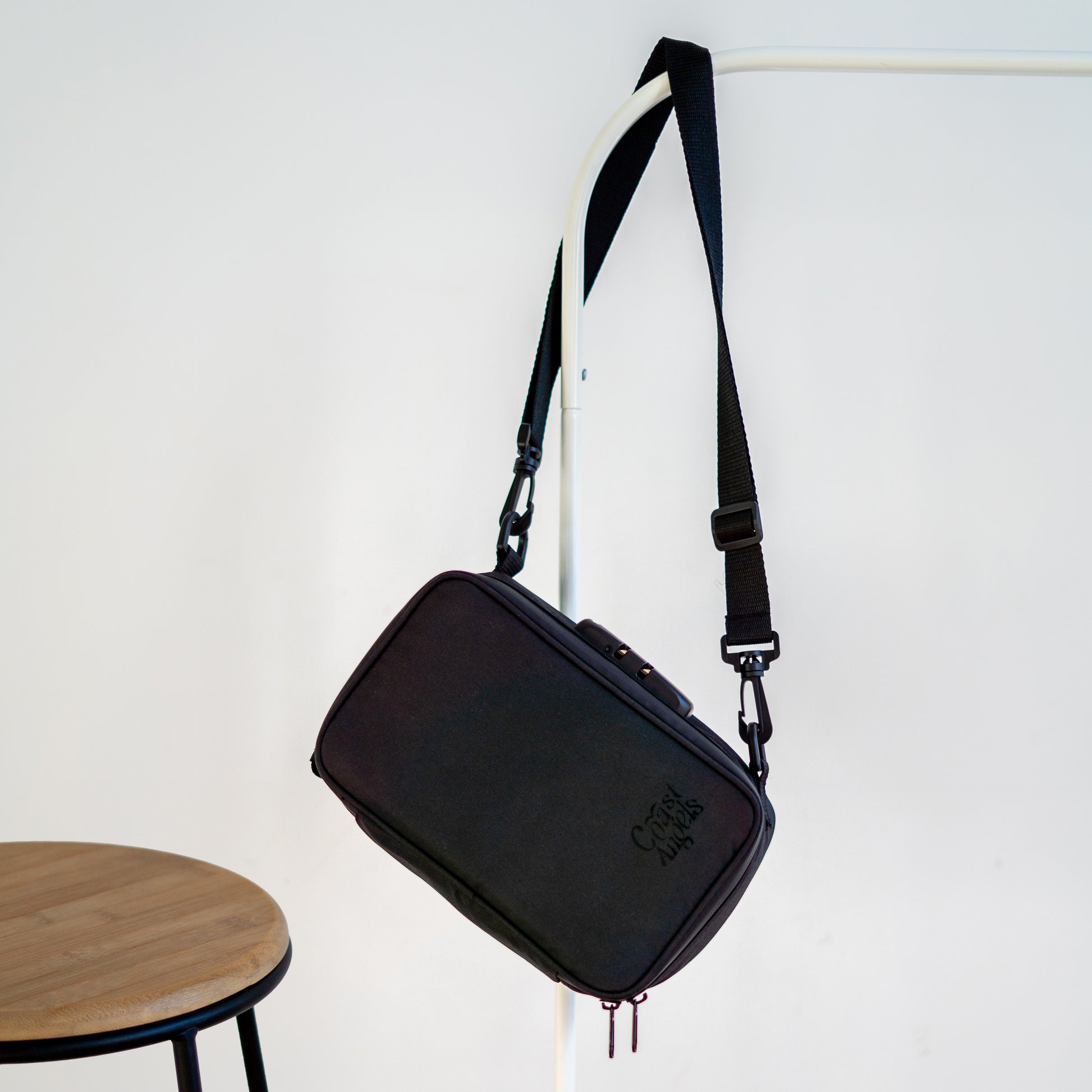 Coast Angels Dalston Bag hanging from a stylish, modern clothes rack, showcasing its sleek design and versatile, discreet style.