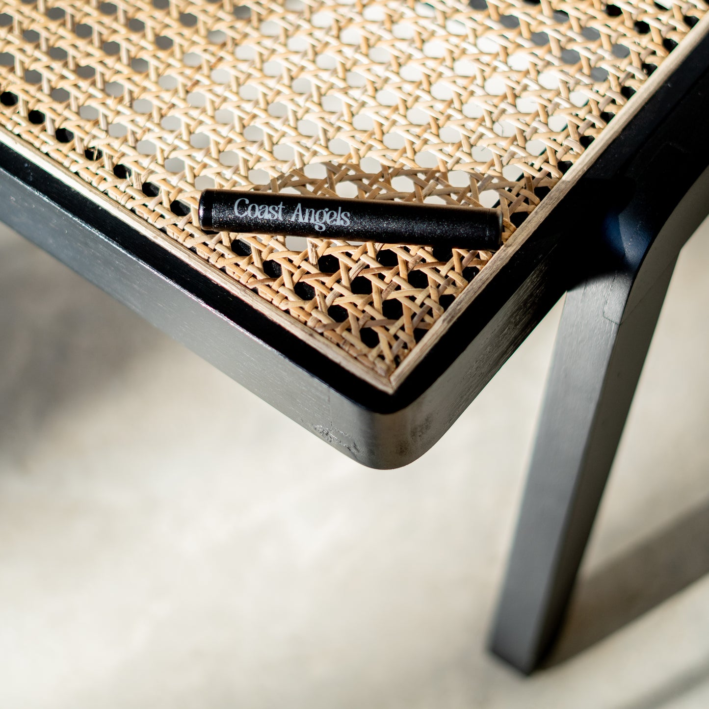 Coast Angels Hackney Smell-proof Tube resting on a rattan chair, showcasing its stylish and discreet design."