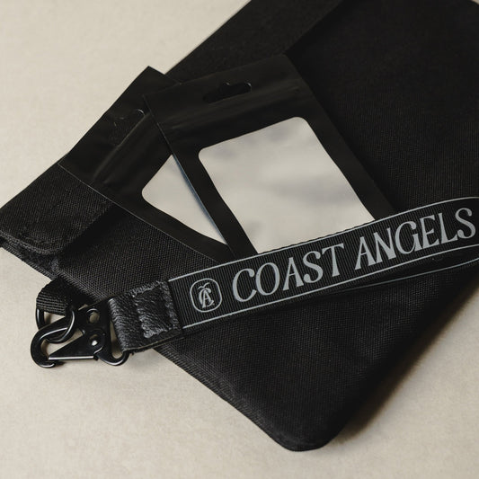 Black bag with 'Coast Angels' strap on a beige background