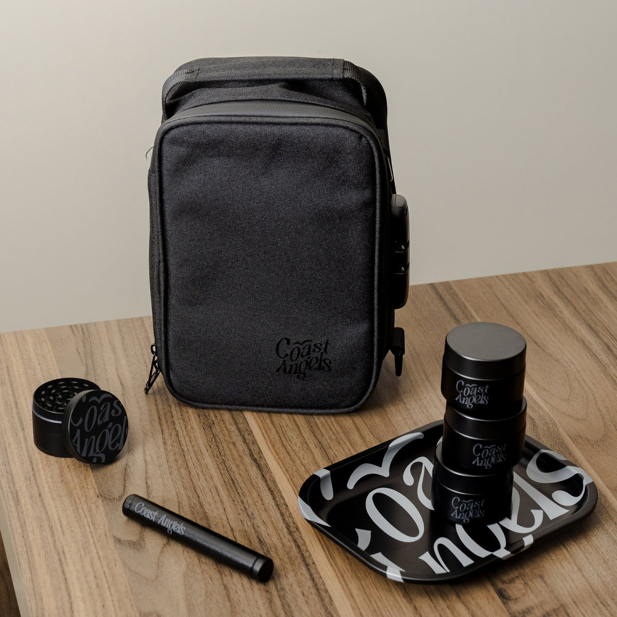 Coast Angels black travel bag with accessories on a wooden surface